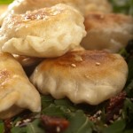 Pierogi nadziewane mięsem kaczki podane z sałatą rukola, suszonymi pomidorami oraz sosem miodowo-balsamicznym